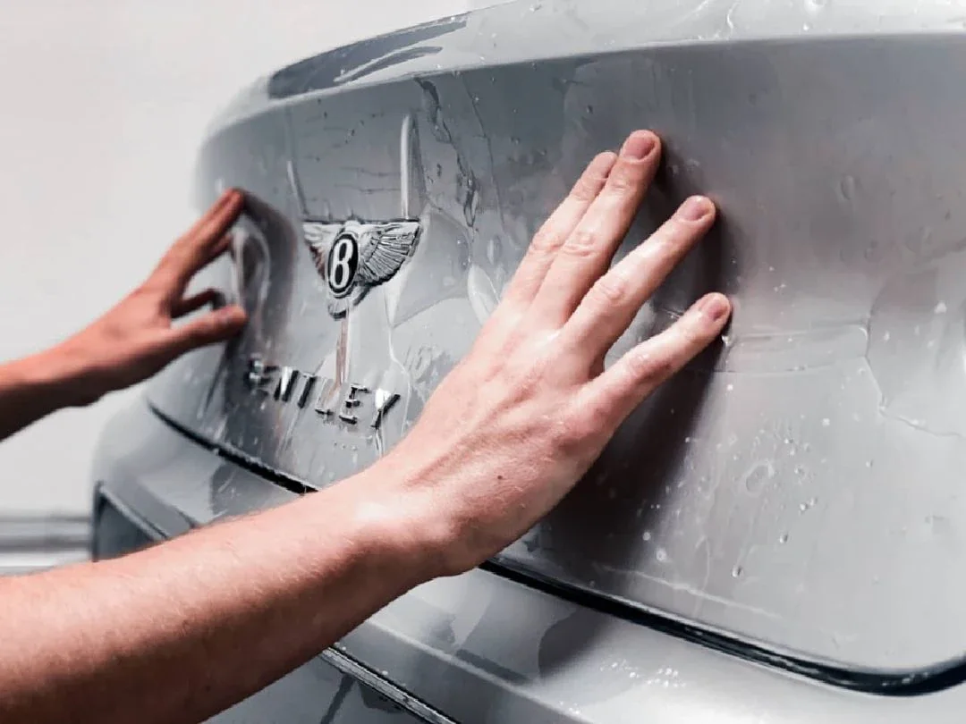 Paint protection film being squeegeed onto a Bentley rear quarter by hand, RainCity PPF Vancouver