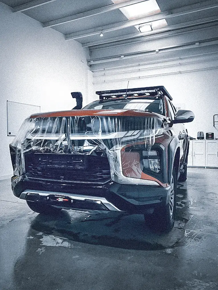 Pattern-cut paint protection film draped over the front end of a truck mid-installation